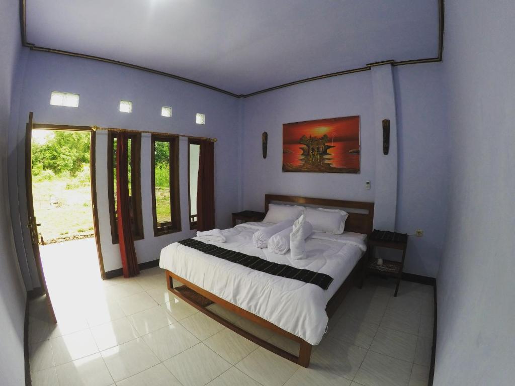 a bedroom with a large bed with white sheets at Danke Lodge in Labuan Bajo