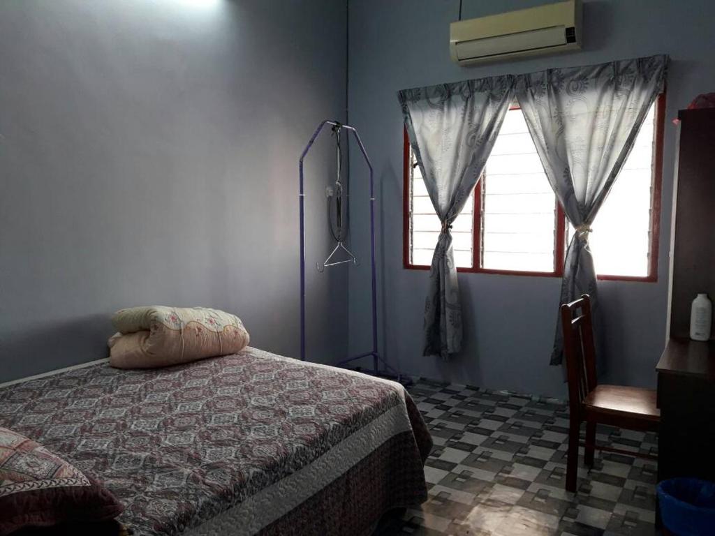 a bedroom with a bed and a window and a chair at Homestay Ustaz in Taiping