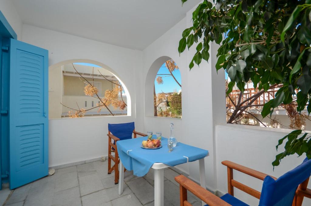una mesa azul y sillas en una habitación con ventanas en Mike's Studios, en Naxos Chora