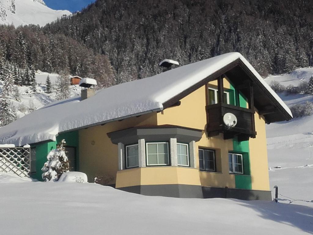 une maison avec de la neige sur le toit dans la neige dans l'établissement Chalet Rustikal, à Virgen