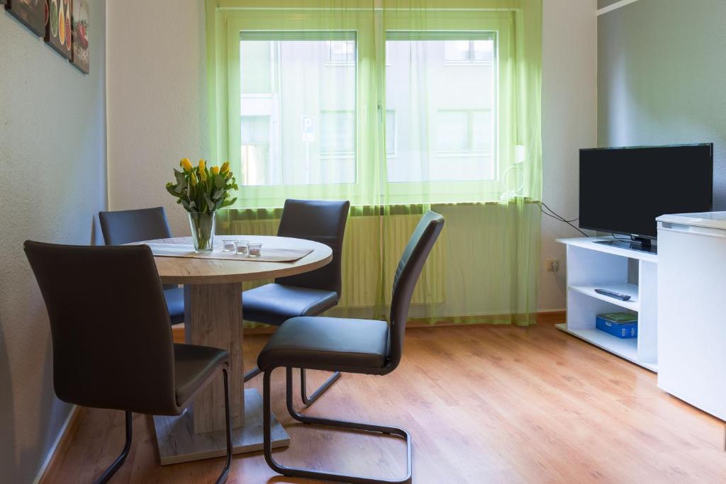 ein Esszimmer mit einem Tisch, Stühlen und einem TV in der Unterkunft Apartment Wideystrasse in Witten