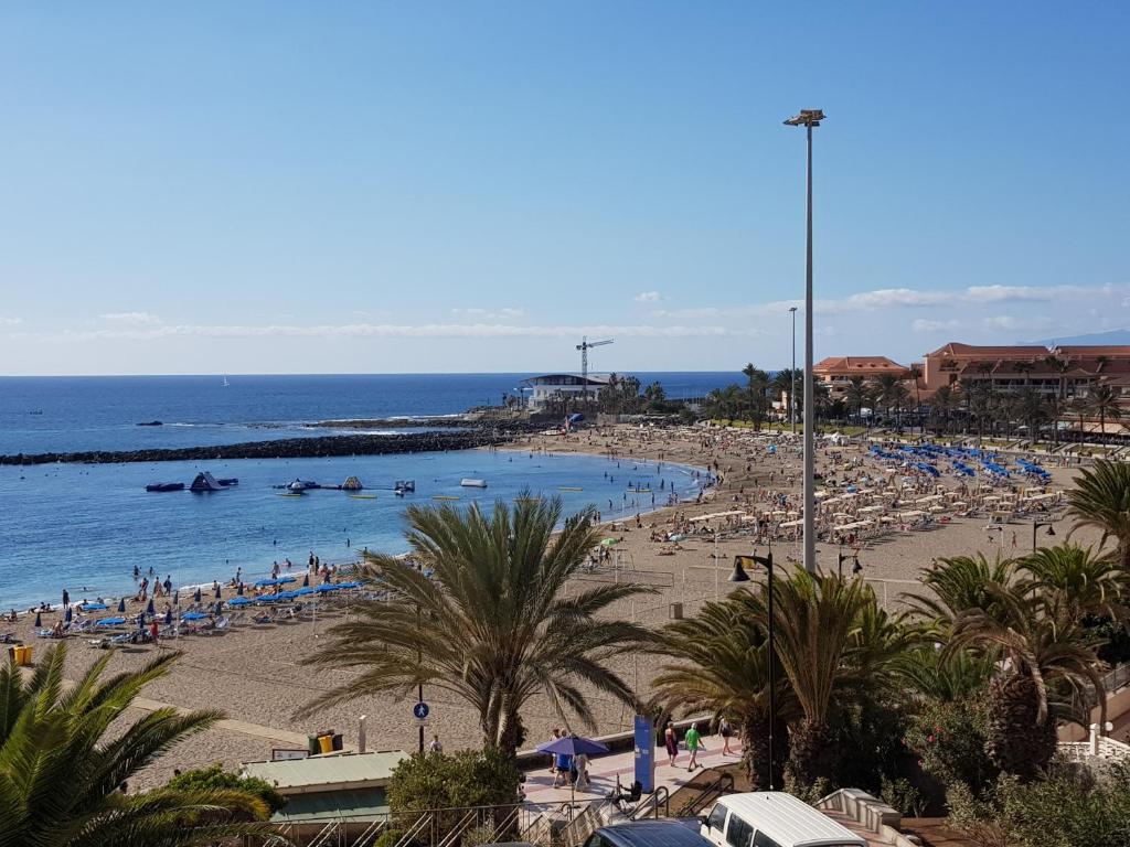 a beach with a bunch of people in the water at Beachfront Los Cristianos in Arona