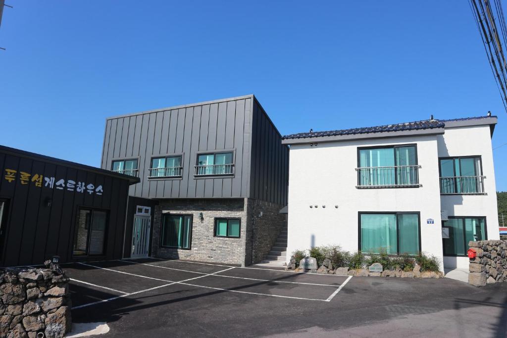 un edificio con un estacionamiento delante de él en Blue Island Guesthouse, en Seogwipo