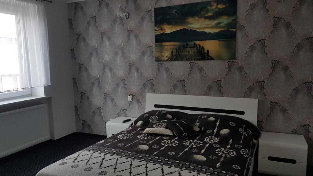 a bedroom with a bed and a painting on the wall at Apartament Centrum 1 in Mikołajki