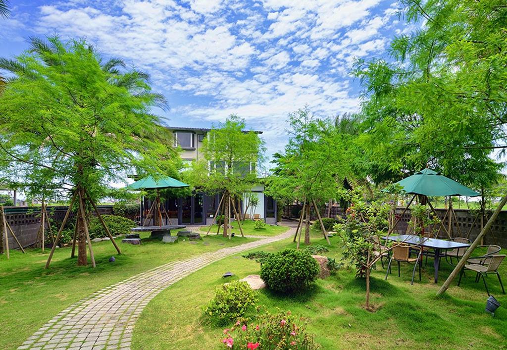 a garden with tables and umbrellas in front of a building at Pokara Resort in Jiaoxi