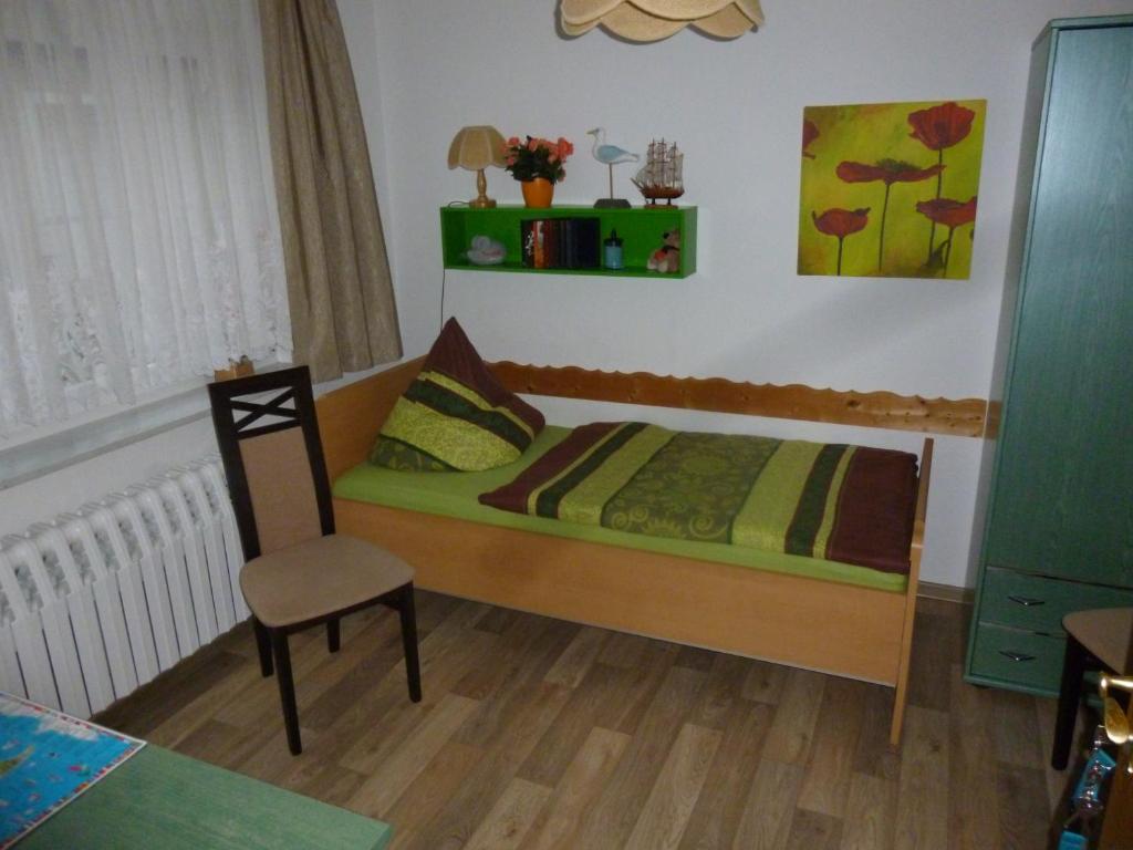 a small bedroom with a bed and a chair at Pension am Peeneufer UG in Wolgast