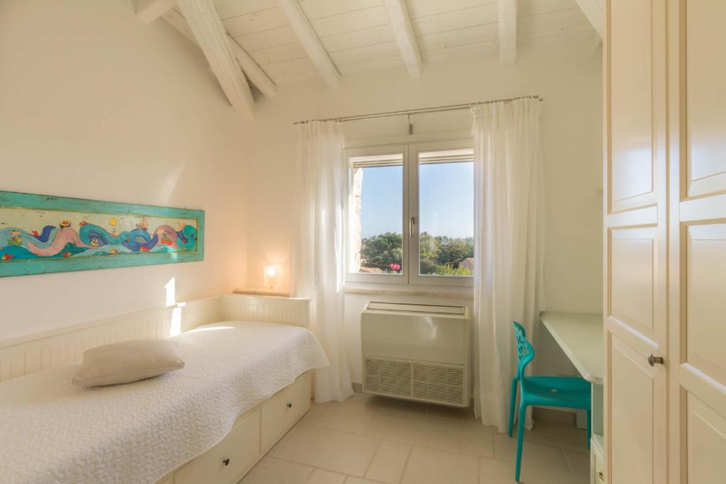 une chambre blanche avec un lit et une fenêtre dans l'établissement Villa Ginestra con piscina e giardino privato a 500 mt dal mare, à Castiadas