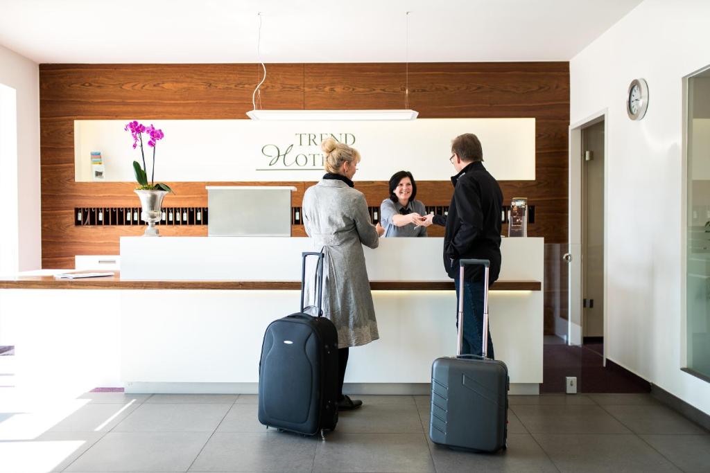 Quelques personnes debout au comptoir avec bagages dans l'établissement Trend Hotel, à Banzkow