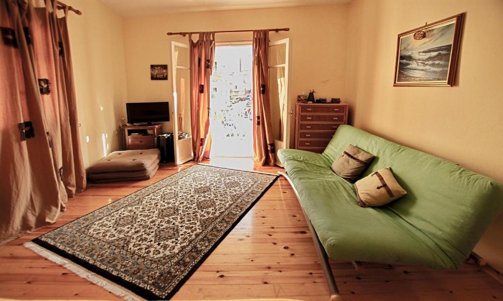 a living room with a green couch on a wooden floor at At the heart of Old Town in Corfu