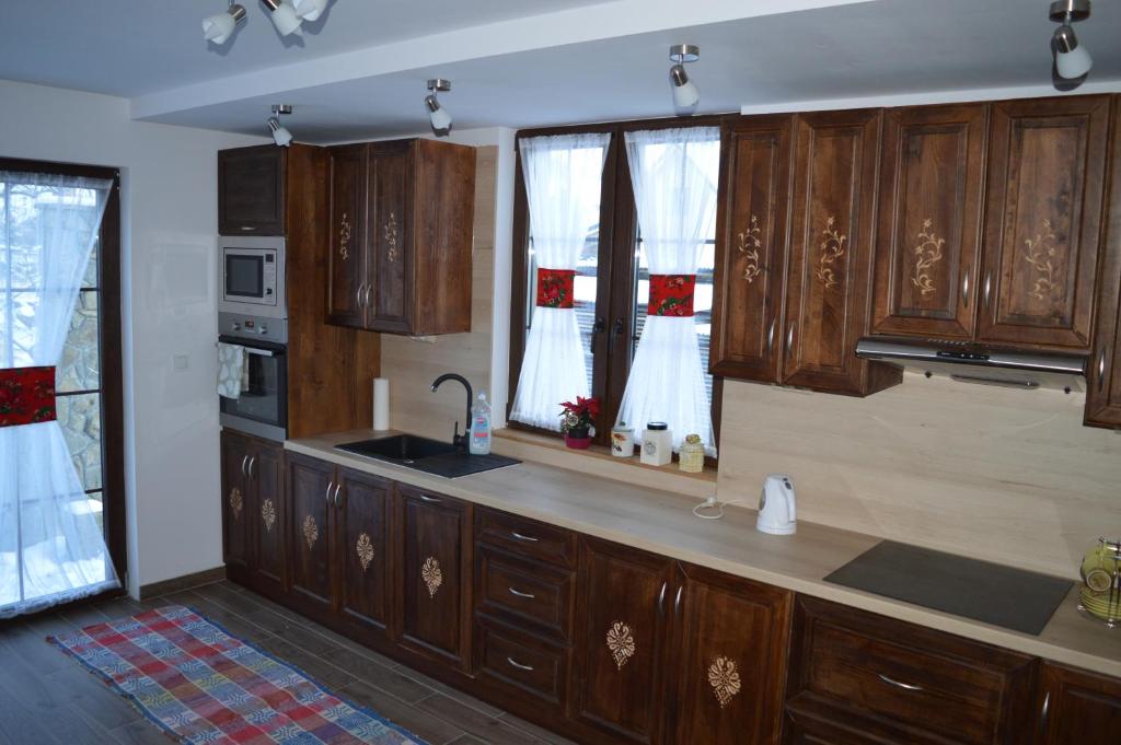 a kitchen with wooden cabinets and a sink at Domek pod Majową Górą in Kacwin