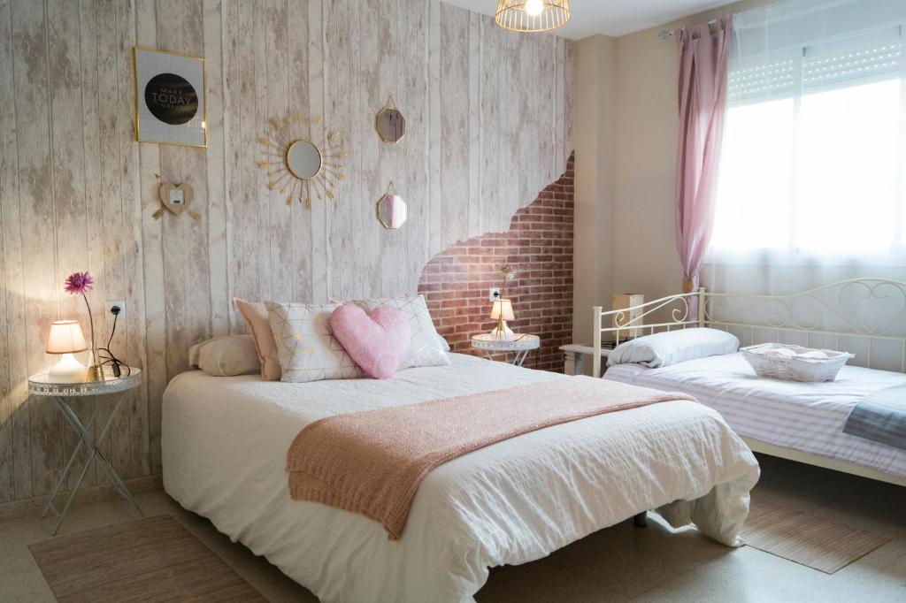 a bedroom with two beds and a brick wall at Rose in Córdoba