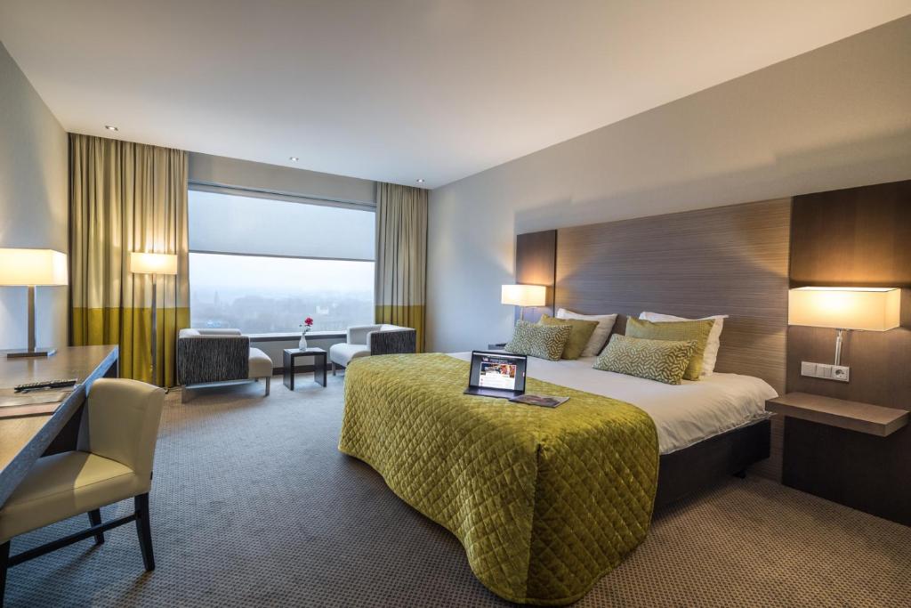 a hotel room with a large bed and a large window at Van der Valk Airporthotel Düsseldorf in Düsseldorf