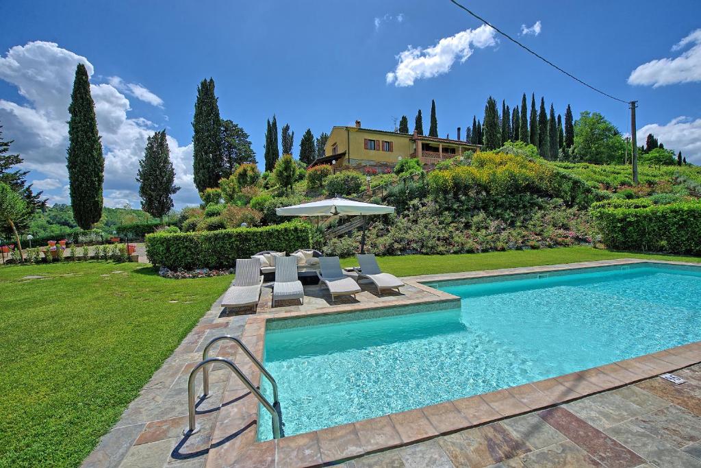 una piscina con sedie e ombrellone in un cortile di Villa Sabrina by PosarelliVillas a San Gimignano