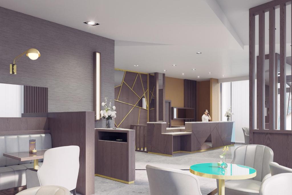 a lobby with white chairs and tables and a kitchen at Maldron Hotel Kevin Street, Dublin City in Dublin
