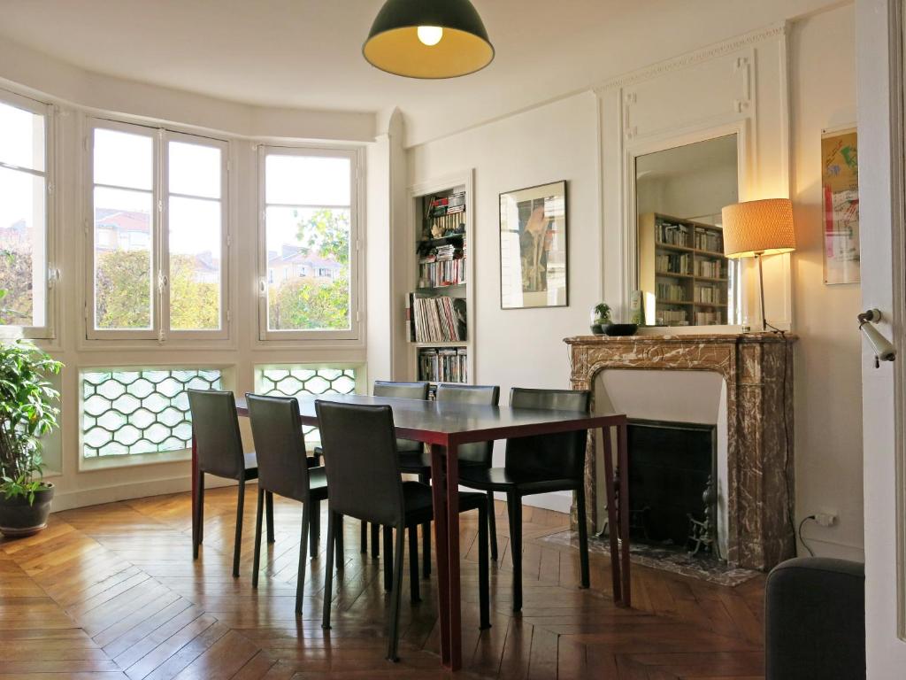 een eetkamer met een tafel en stoelen en een open haard bij Charme Vaugirard Procession CityCosy in Parijs
