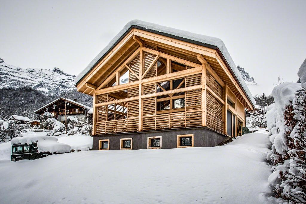una cabaña de madera en la nieve cubierta de nieve en Chalet lux et Design en Servoz