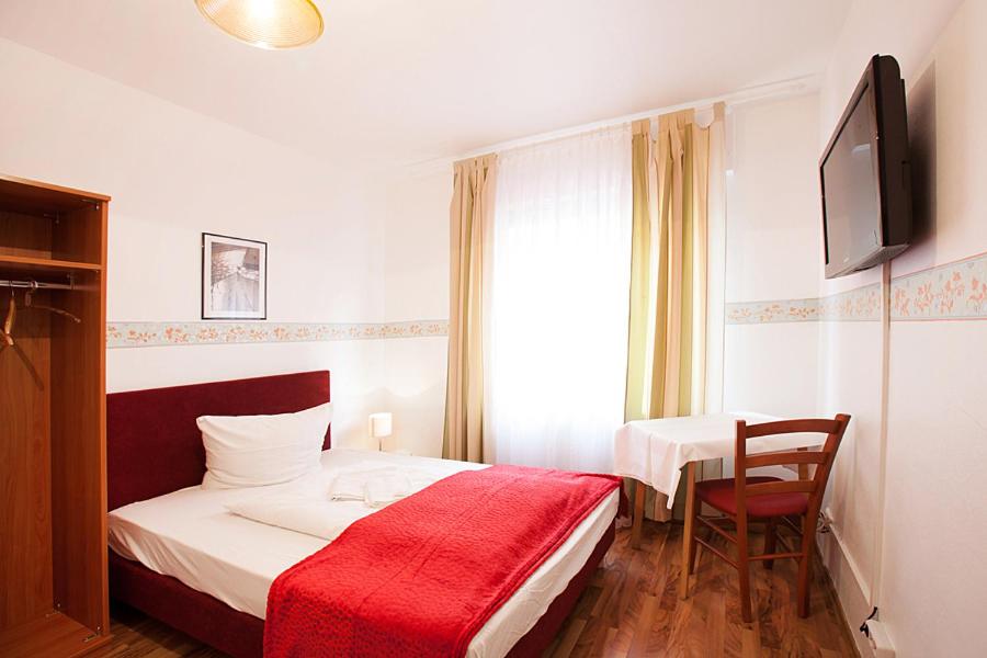 a bedroom with a bed and a table with a red blanket at Pension Jasmin in Pforzheim
