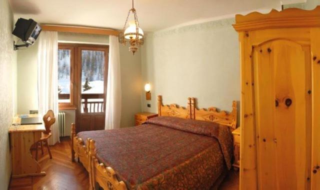a bedroom with a wooden bed and a window at Hotel Banchetta in Sestriere