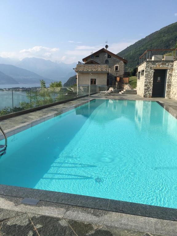 een groot blauw zwembad met bergen op de achtergrond bij Paradiso del lago in Bellano