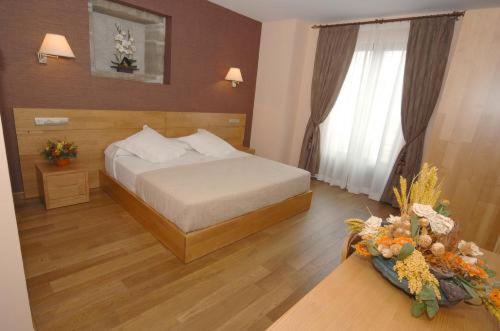 a bedroom with a bed and a table with flowers at Hotel O Desvio in Santiago de Compostela