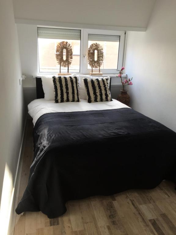 a black and white bed in a room with two windows at appartementen zeespiegel in Zandvoort