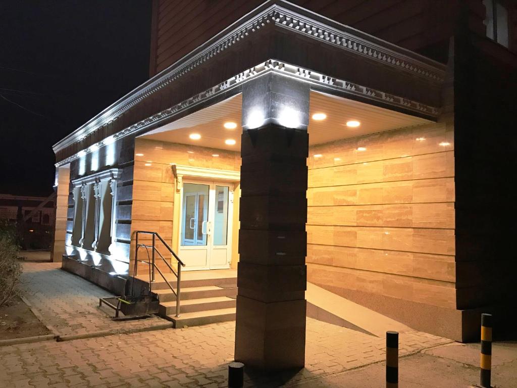 a wooden building with lights on it at night at Tengri Hotel in Atyraū