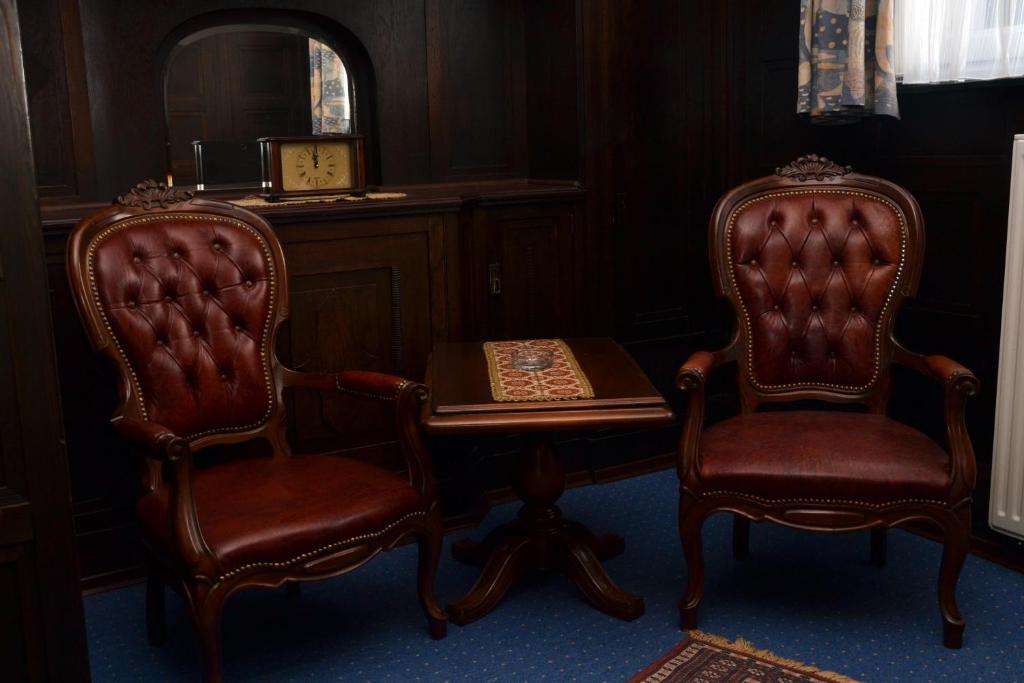 2 stoelen en een tafel in een kamer met een bureau bij Hotel An der Karlstadt in Bremerhaven