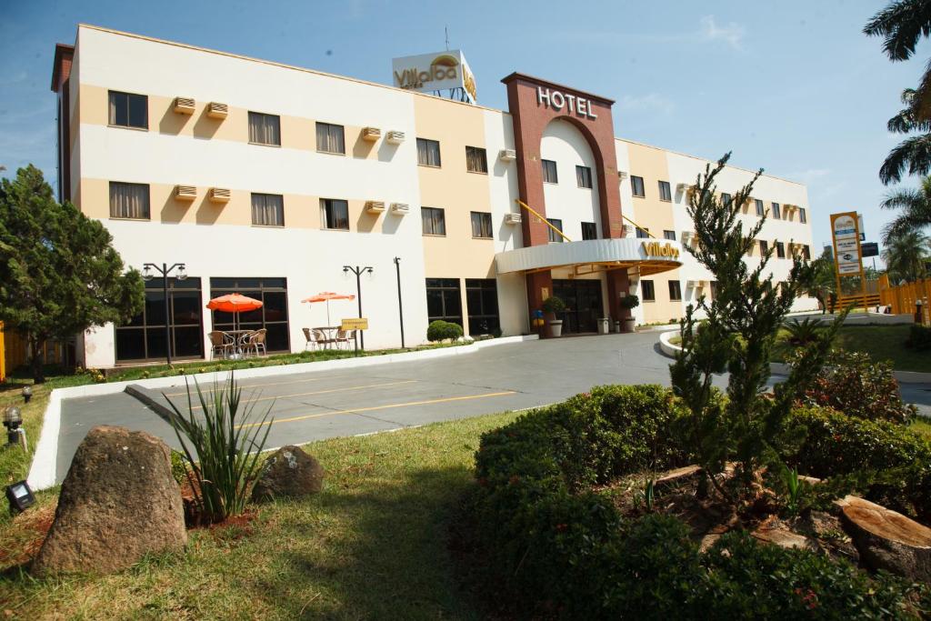 a hotel with a parking lot in front of it at Villalba Hotel in Uberlândia