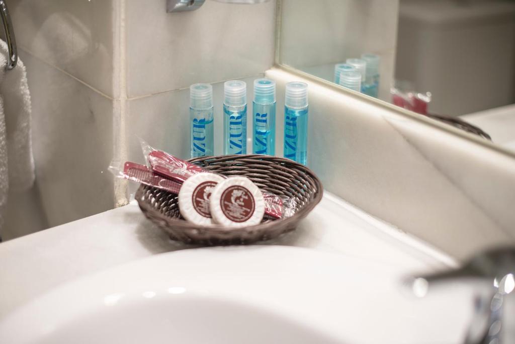 - Cesta de cepillos de dientes y pasta de dientes en el lavabo del baño en Hotel Concordy, en Madrid
