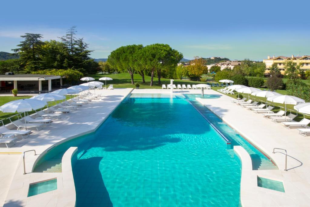 a swimming pool with white chairs and umbrellas at Hotel Smeraldo in Abano Terme