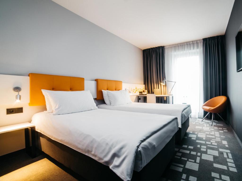 a hotel room with two beds and a desk at Q Hotel Kraków in Kraków