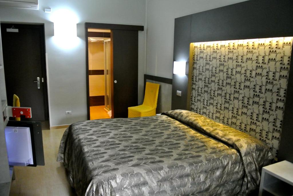 sypialnia z łóżkiem i żółtym krzesłem w obiekcie Hotel Dei Mille w Rzymie