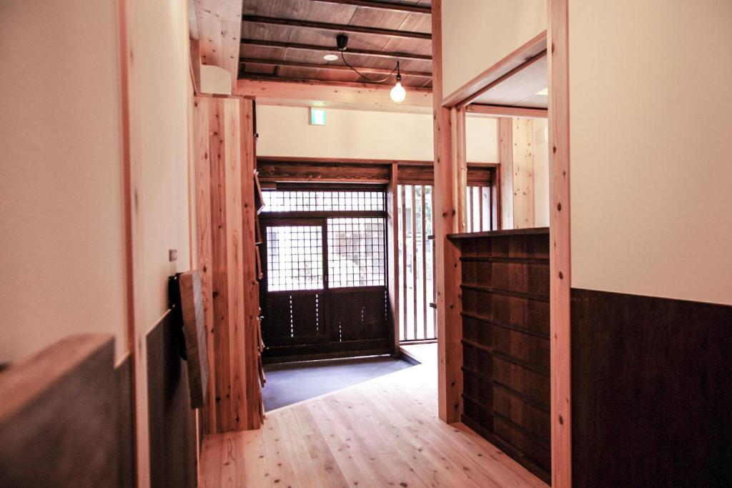 korytarz z drzwiami prowadzącymi do pokoju z drewnianą podłogą w obiekcie Poly Hostel 2 Namba w Osace