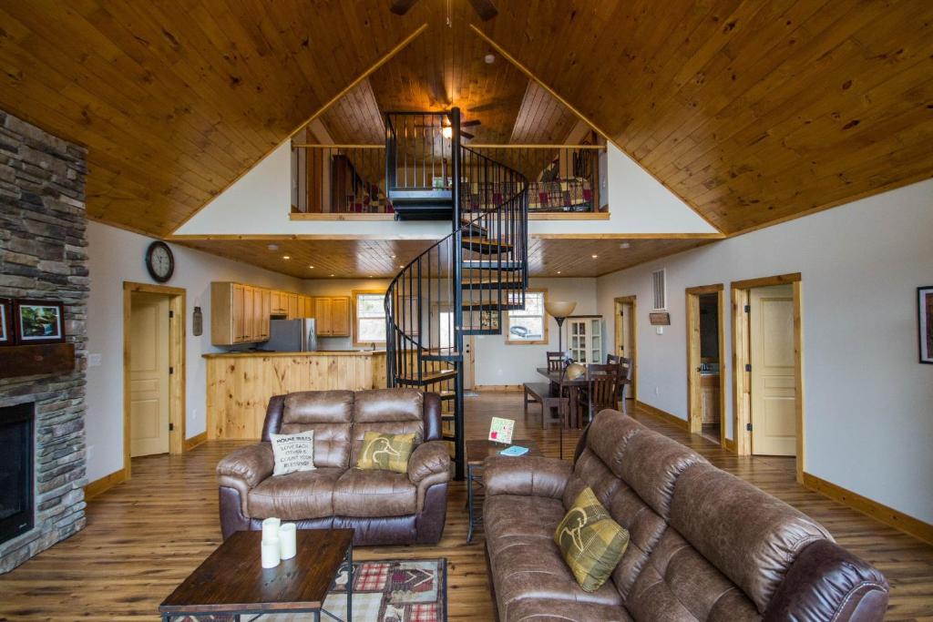 a living room with leather furniture and a spiral staircase at Tree Top cabin on the Shenandoah River in Luray