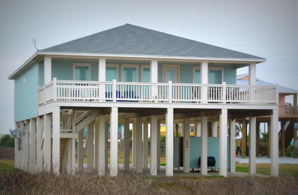 ein großes blaues Haus mit weißen Säulen und einem Balkon in der Unterkunft Surf And Sand Home in Stingaree