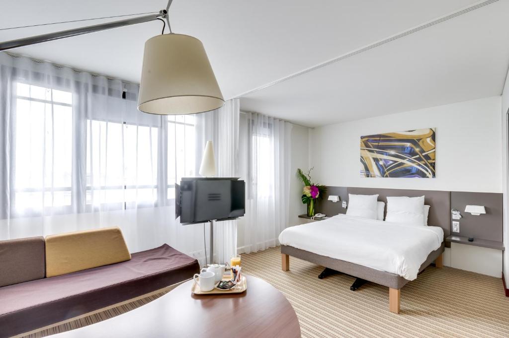 une chambre d'hôtel avec un lit et un canapé dans l'établissement Novotel Suites Paris Montreuil Vincennes, à Paris
