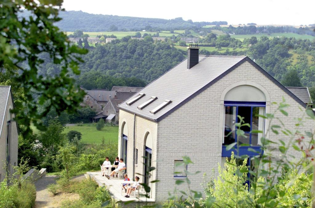 un groupe de personnes assises sur la terrasse couverte d'une petite maison dans l'établissement Résidence Durbuy, à Durbuy