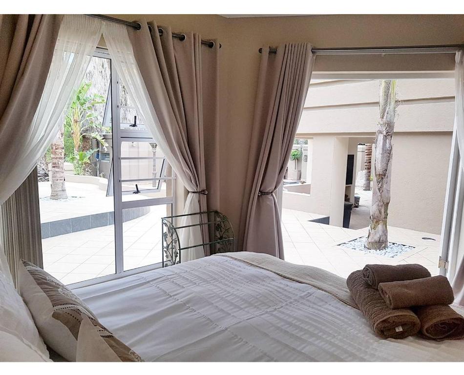 a bedroom with a bed and a large window at Oudtshoorn Guest House in Oudtshoorn