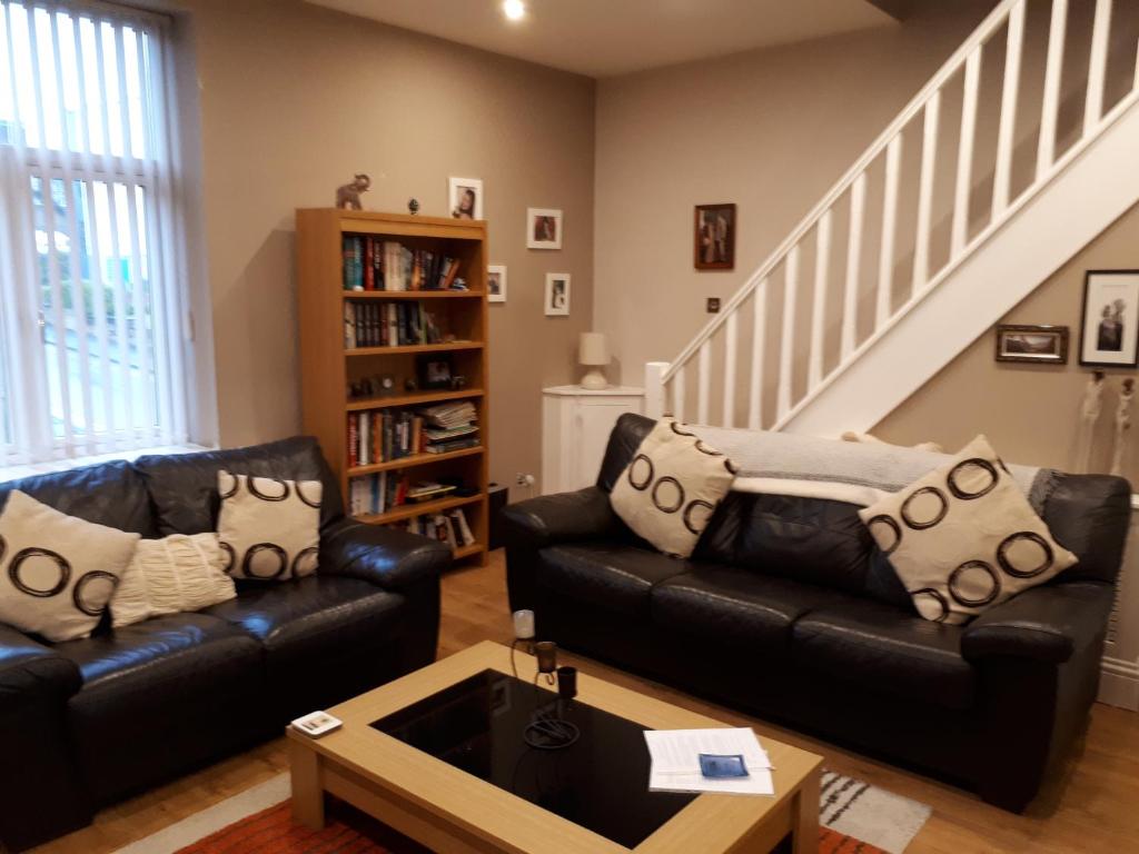 a living room with two leather couches and a staircase at Bonny Colne On The Hill in Colne