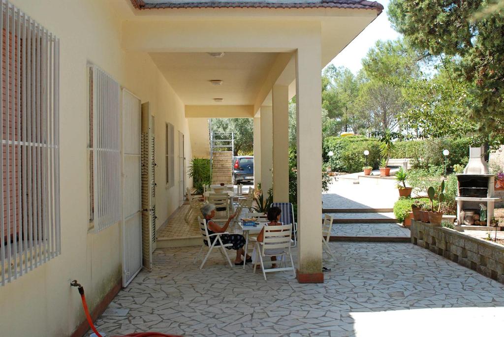 un patio con sedie e un tavolo su una casa di Villa con piscina e campo da tennis ad Avola