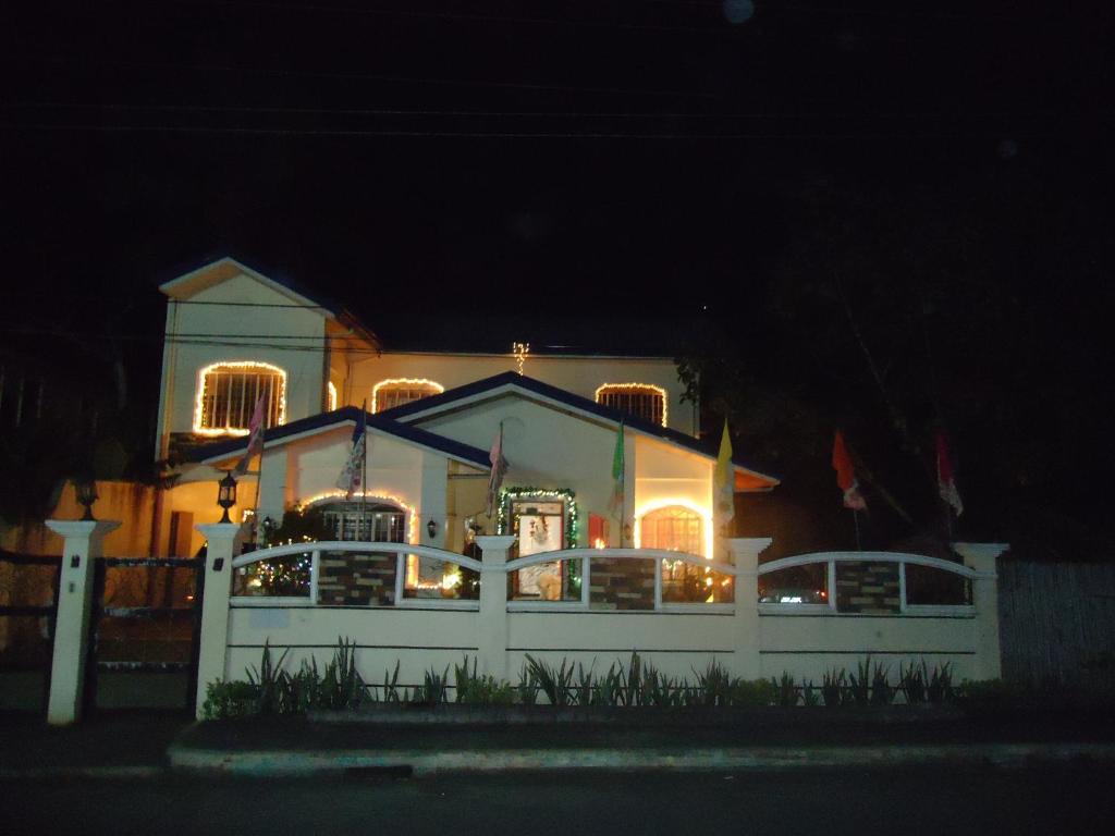 a house with a white fence in front of it at night at Donsol Aguluz Homestay in Donsol