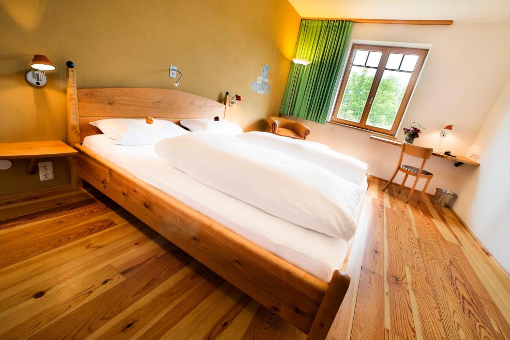 Cama grande en habitación con suelo de madera en BIO-Hotel Alter Wirt en Grünwald