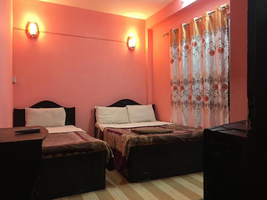 2 camas en una habitación con paredes rojas en Pashupati Darshan Hotel en Katmandú