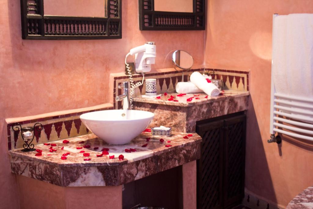 baño con lavabo con rosas rojas en la encimera en Riad Alya, en Fez
