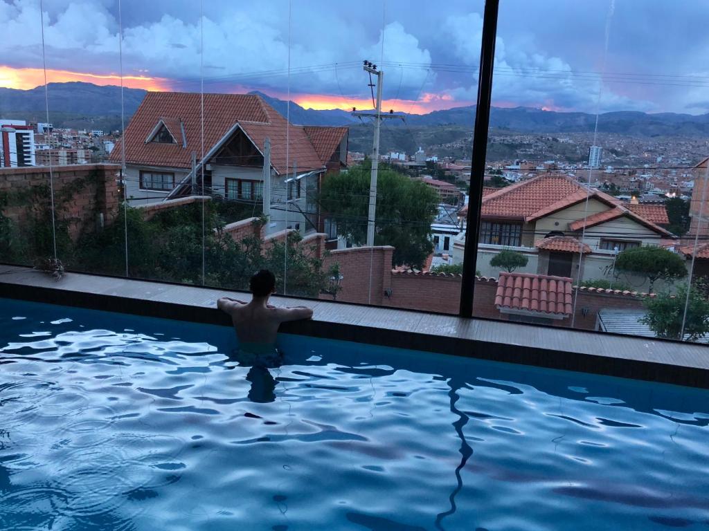 a man in a swimming pool with a view of a city at Apartment with beautiful landscape in Sucre