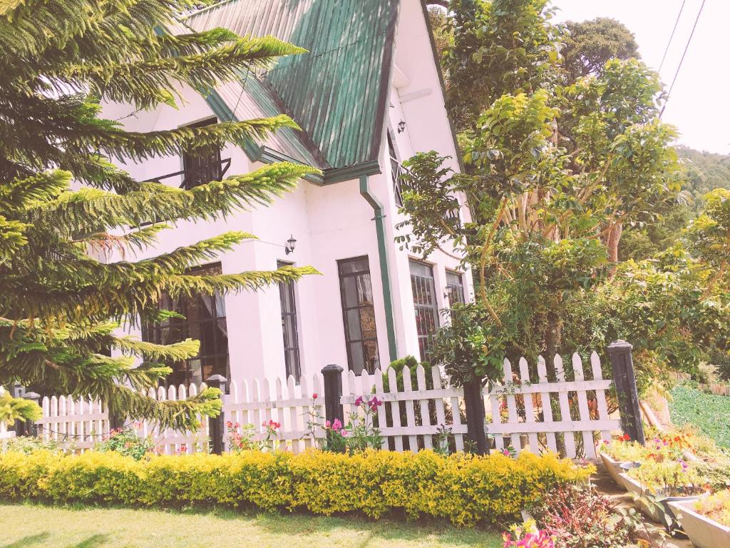 a white house with a white picket fence at Sherwood Cottage in Nuwara Eliya