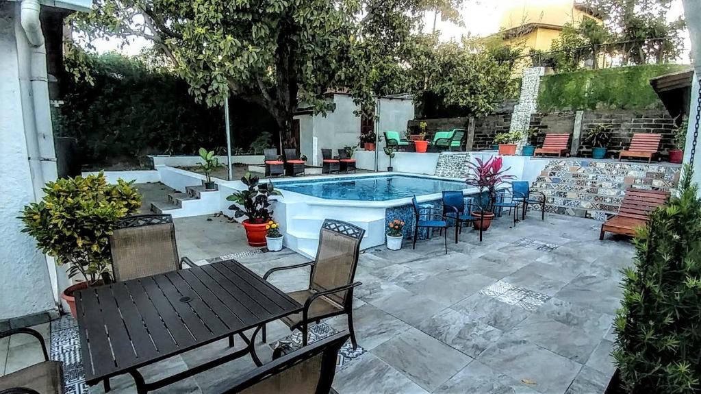 un patio con piscina, mesas y sillas en El Mirador Suites and Lounge en Managua