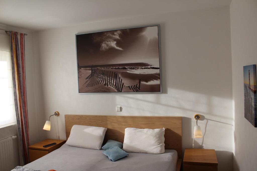 ein Schlafzimmer mit einem Bett und einem Bild an der Wand in der Unterkunft Das GrachtenDOMiZiL Greetsiel in Greetsiel