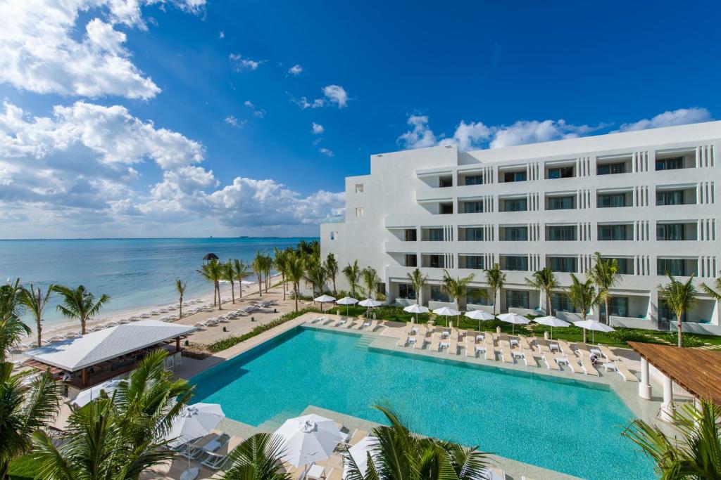 a beach with a large swimming pool and a large building at Izla Beach Front Hotel in Isla Mujeres