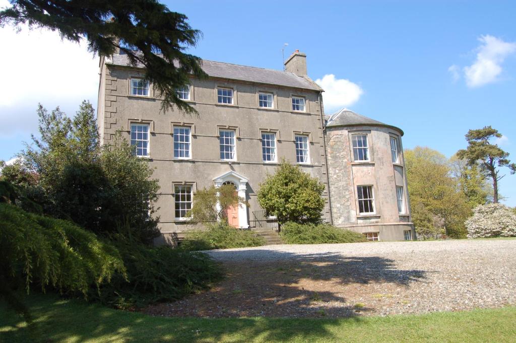 una vieja casa de piedra con un árbol delante en Ballydugan Country House en Downpatrick